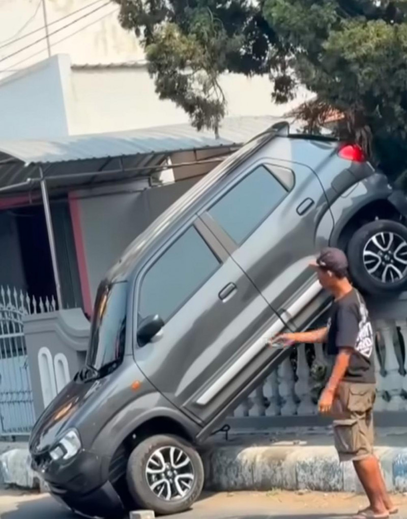 Mobil Suzuki S-Presso Tersangkut Di Atas Pagar Rumah Warga Di Jombang,Di Duga Kurang Kuasai Gigi Mundur
